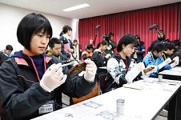 瓶についている指紋の鑑識を体験する参加者たち＝春日井市の県警察学校で