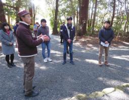 度会町で取り組む「地元ツーリズム」を愛知大の学生に紹介する御村さん（左手前）＝度会町上久具の久具都比売神社で