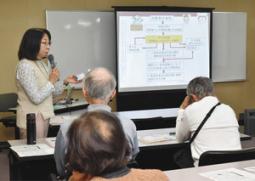 患者がテレビ番組やCMの影響を受けていると指摘する半谷准教授(左)=日進市民会館で
