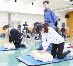 消防職員の指導で心臓マッサージを学ぶ学生たち＝大府市消防本部で
