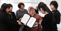 版画クラブの仲間に卒業証書を披露し、祝福を受ける西松さん＝岡崎市の愛知産業大で