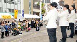 愛知東邦大吹奏楽団の演奏を楽しむ人たち＝名東区の地下鉄藤が丘駅前で