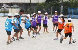 寺田さん（左から３人目）からサッカーの授業を受ける児童たち＝神戸町の下宮小で