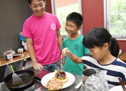 伊丹さん（左端）の手ほどきでハンバーガーを作る子どもたち＝豊田市足助町の宿泊施設「百年草」で