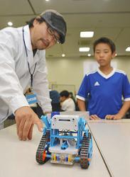 組み上げたロボットの動きを確認する生徒（右）と西山さん＝瀬戸市蔵所町の瀬戸蔵で