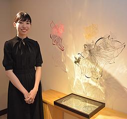 空間と照明を生かし、展示にこだわった金魚の切り絵作品と神田さん＝春日井市のギャラリーカフェわッつで