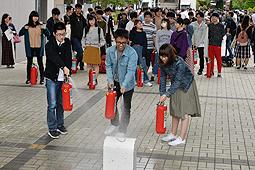 消火器の放水を体験する学生＝鈴鹿市の鈴鹿医療科学大で