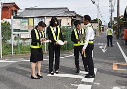 実際に事故が起きた交差点で、捜査員から説明を受ける学生ら＝津市修成町で