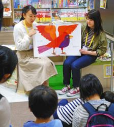 カラフルな動物が登場する英語の絵本で、読み聞かせをする学生たち＝日進市赤池町で