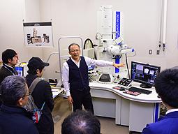 メーカーの担当者を前に、透過型電子顕微鏡を説明する岩田准教授（中）＝豊田市八草町で