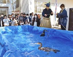 足立鵜匠に教わりながら、手縄を持って鵜を操る学生＝関市桐ケ丘の中部学院大関キャンパスで