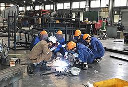金属製品製造「タイメック」で金属加工を教わる高校生たち＝関市武芸川町八幡で