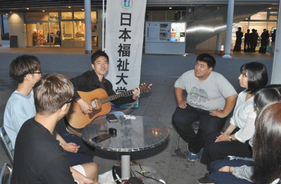 ギターの音色とともに、歌を歌う学生たち＝東海市の名鉄太田川駅前で