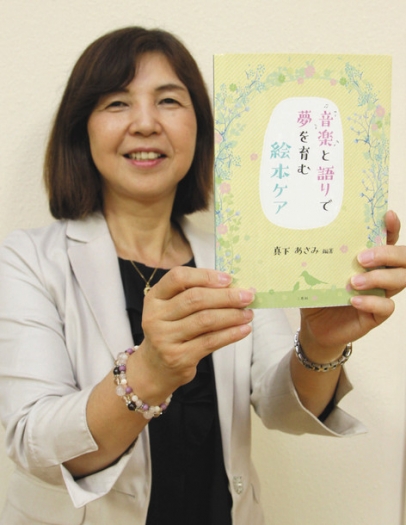 絵本ケアについてまとめた初の書籍を紹介する真下さん＝稲沢市の愛知文教女子短大で