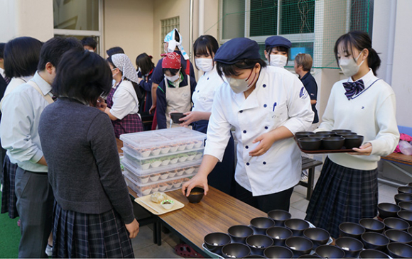 登校してきた生徒に「１００円朝食」を振る舞うボランティアの生徒たち＝守山区の菊華高で