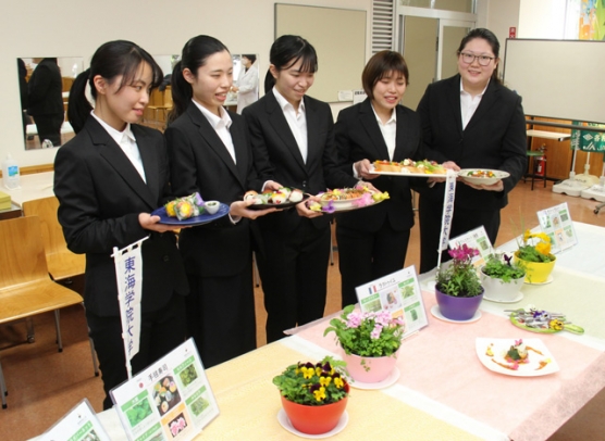 鉢植えの食用花やハーブを使って作った料理を手にする学生たち＝各務原市那加桐野町の東海学院大で